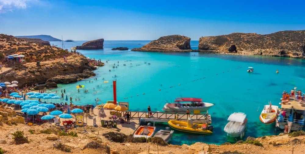 An image of the Blue Lagoon featuring a small to medium amount of people and some tourist facilities like beach umbrellas.