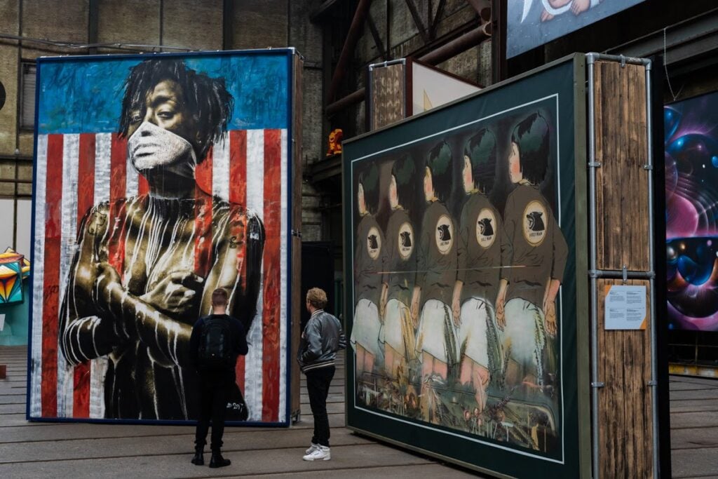 A work by Eddie Colla, featuring an American flag and a Black character in the foreground wearing a face covering.