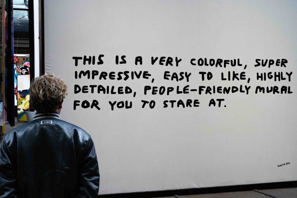 A mural reading "This is a very colorful, super impressive, easy to like, highly detailed, people-friendly mural for you to stare at."