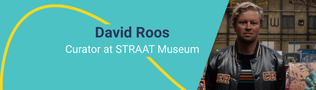 A picture of the curator of STRAAT Museum, standing in front of the artworks.