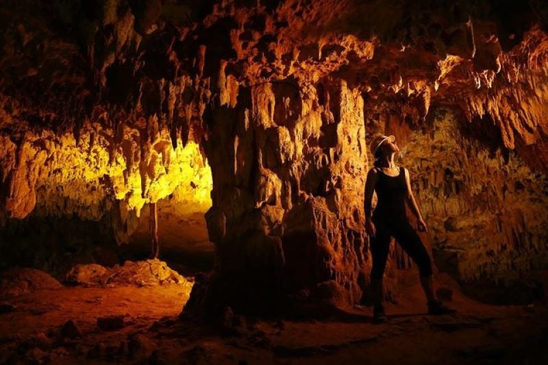 A woman wearing a helmet admiring the spires in an illuminated cave