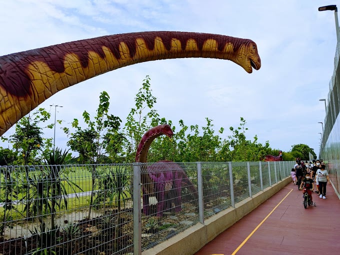 A dinosaur towers over passerby as they make their way along the Changi Jurassic Mile in Singapore