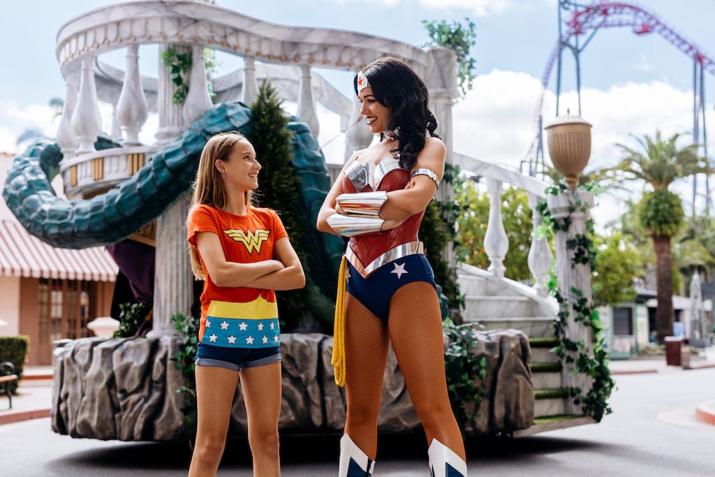 a kid posing with a staff of the theme park in a Wonder Woman custom