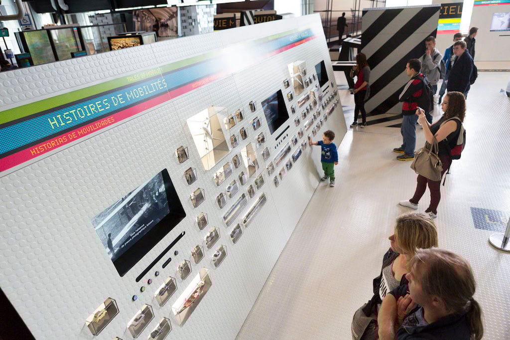 visitors standing in front of a display board at the city of science and industry - one of the best things to do with kids in paris