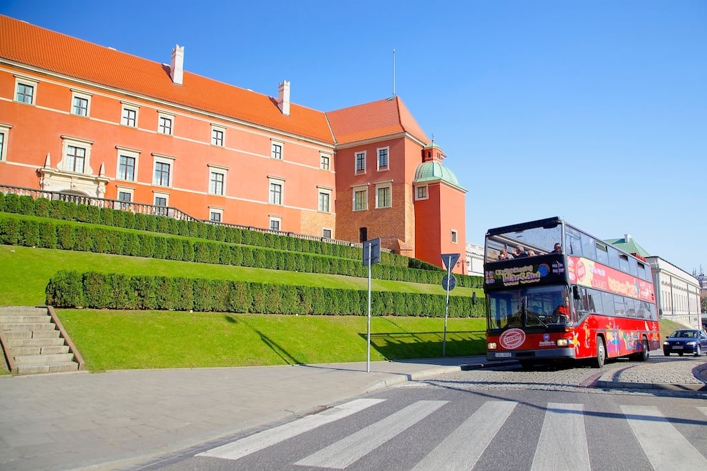 hop-on hop-off bus tour stopping in front of a light orange building